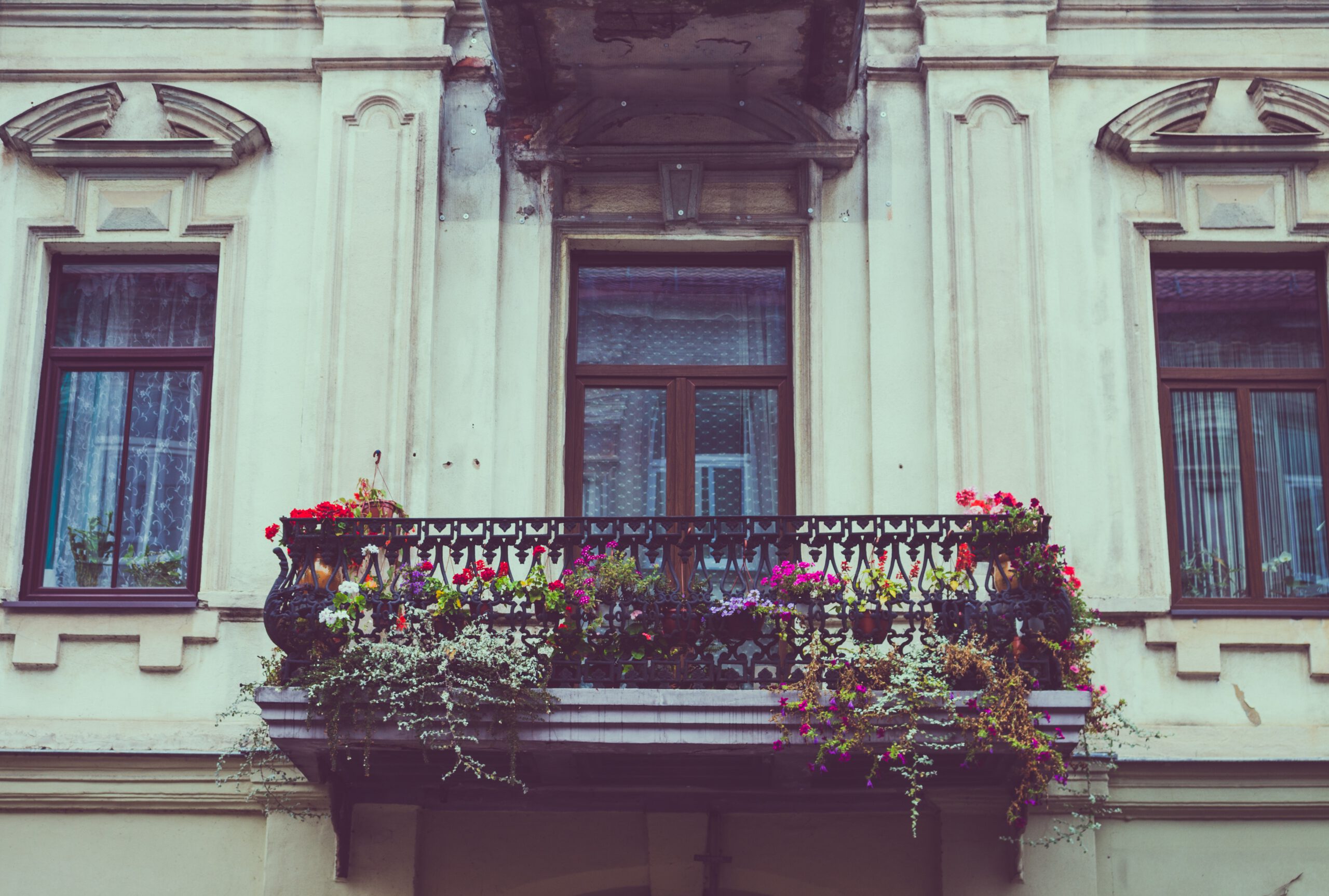 Balkon obłożony kolorowymi kwiatami w starej kamienicy