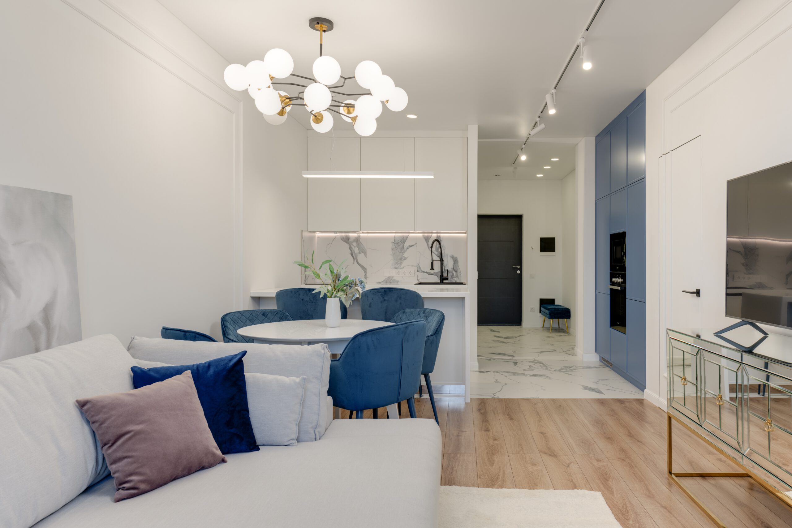Nowoczesny biało-niebieski salon z aneksem kuchennym w małym mieszkaniu